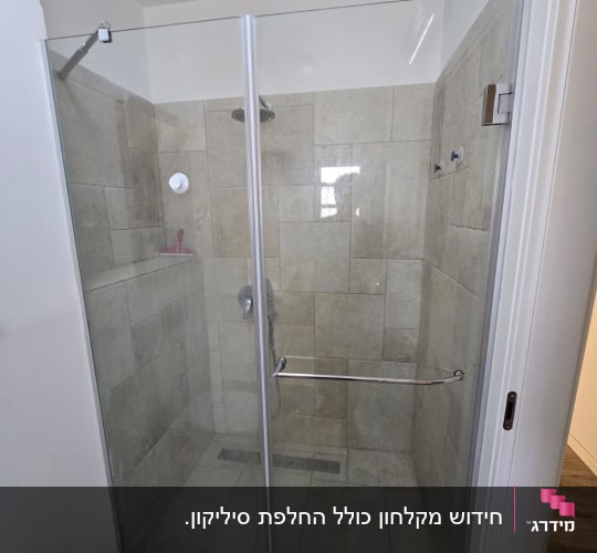 מקלחון זכוכית עם ראש מקלחת וקיר אריחים